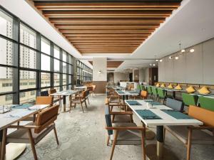 um restaurante com mesas, cadeiras e janelas em Hilton Garden Inn Jincheng Gushuyuan em Jingcheng