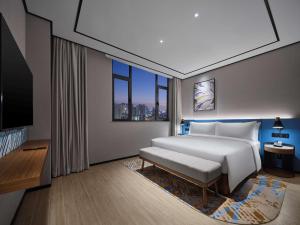 a bedroom with a white bed and a large window at Hilton Garden Inn Jincheng Gushuyuan in Jincheng