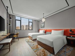 ein Hotelzimmer mit 2 Betten und einem Schreibtisch in der Unterkunft Hilton Garden Inn Jincheng Gushuyuan in Jingcheng