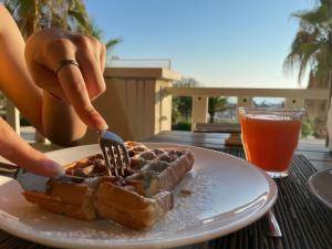 a person eating a waffle on a plate with a fork at Yes Hotel Touring & SPA in Rimini