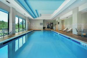 a swimming pool with blue water in a building at Embassy Suites By Hilton Alpharetta Halcyon in Alpharetta