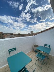 2 Tische und Stühle auf einem Balkon mit Aussicht in der Unterkunft Duplex de charme avec terrasses in Nîmes