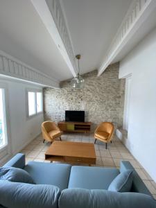 ein Wohnzimmer mit einem Sofa und einem TV in der Unterkunft Duplex de charme avec terrasses in Nîmes