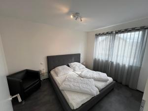 um quarto com uma cama com lençóis brancos e uma janela em Ferienwohnung Strobel em Niedereschach