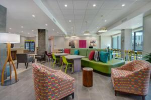 a lobby with a green couch and tables and chairs at Home2 Suites By Hilton Burleson in Burleson