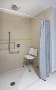 a bathroom with a chair and a shower curtain at Hampton by Hilton Veracruz Boca Del Rio in Veracruz