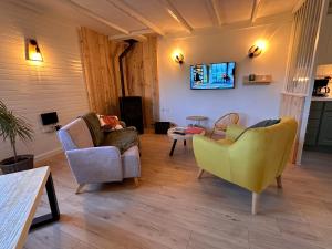 a living room with two chairs and a tv at L’impasse - Au bord de l’eau in Épagne-Épagnette