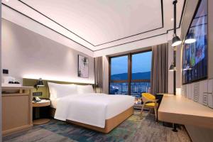 a hotel room with a bed and a desk and a window at Hilton Garden Inn Changsha Yuelu in Changsha