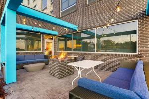 un patio con sillas azules y una mesa blanca en Tru By Hilton Raleigh Garner, en Garner