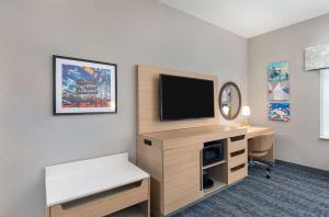 ein Hotelzimmer mit einem TV und einem Schreibtisch mit einem Schreibtisch in der Unterkunft Hampton Inn Albertville, Al in Albertville