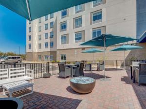 un patio avec des tables, des chaises et des parasols en face d'un bâtiment dans l'établissement Hampton Inn & Suites Williamstown Ark Encounter, Ky, à Williamstown