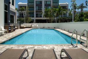 einen Pool mit Stühlen und ein Gebäude in der Unterkunft Hampton Inn Delray Beach in Delray Beach