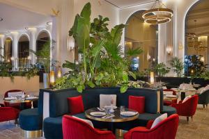 a restaurant with a blue couch and tables and chairs at Maysan Doha, LXR Hotels & Resorts in Doha