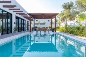 杜哈的住宿－Maysan Doha, LXR Hotels & Resorts，一个带椅子的游泳池以及一座房子