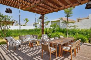 una terraza de madera con mesa y sillas de madera en Maysan Doha, LXR Hotels & Resorts, en Doha