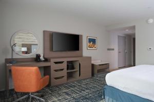 a hotel room with a bed and a desk with a television at Hampton Inn & Suites Manistee, Mi in Manistee