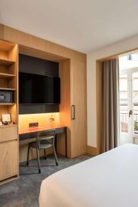 ein Hotelzimmer mit einem Bett, einem Schreibtisch und einem TV in der Unterkunft Arts Hotel Porto, Tapestry Collection By Hilton in Porto