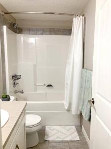 a white bathroom with a tub and a toilet and a sink at Mahogany Escape - Your Calgary Oasis in Calgary