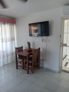 a dining room with a table and a television on a wall at Tropical Optimal Tropicana Sur in Sosúa