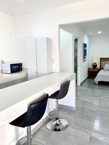 a kitchen with a white counter and two chairs at 5th Av Studio Close to the Beach ADO Ferry & Mall in Playa del Carmen