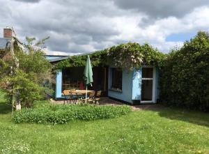Casa azul con mesa y sombrilla en Blaues Haus Neu Reddevitz, en Lancken-Granitz