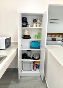 a kitchen with a white pantry with a microwave at 5th Av Studio Close to the Beach ADO Ferry & Mall in Playa del Carmen +10 photos