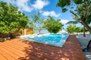 a swimming pool on a wooden deck next to the beach at Beachfront Villa Island Pearl Gold Standard Certified in Caye Caulker