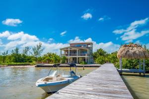 a boat docked at a dock in front of a house at Beachfront Villa Island Pearl Gold Standard Certified in Caye Caulker