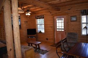 a living room of a log cabin with a chair and a television at Sky Cabin in Ruidoso