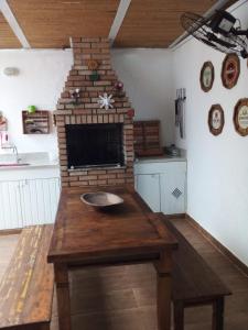 a kitchen with a brick fireplace and a wooden table at Juquehy Casa para Famílias em condomínio in Juquei