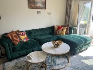 a living room with a green couch and two tables at Central Comfort Room in heart of Oslo, Majorstuen in Oslo
