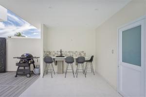 a white room with a table and stools at Villa Varia in Rarotonga