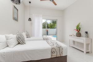 a white bedroom with a bed and a pool at Villa Varia in Rarotonga