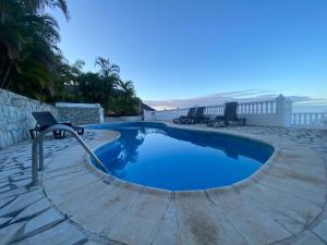 a swimming pool with chairs around it next to the beach at Apartamentos y Bungalows Finca Colón in Fuencaliente de la Palma