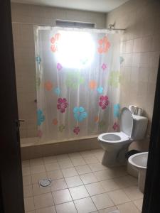 a bathroom with a toilet and a shower curtain with flowers at Talabay apartment 20109 in Al Burj