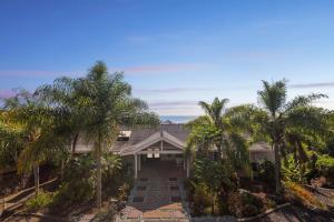 une maison avec des palmiers devant dans l'établissement Pu'ukala Sunset Estate with Amazing Ocean Views! home, à Kailua-Kona