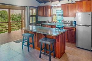 a kitchen with a counter with a refrigerator and stools at The Cottages at Island Pearl Gold Standard Certified in Caye Caulker