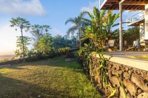a house with a stone wall next to the ocean at Charming Pu'ukala Sunset - Near Hiking and Golf home in Kailua-Kona