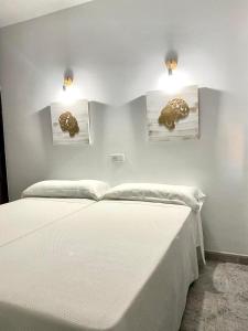 1 dormitorio con 1 cama blanca y 2 cuadros en la pared en Hostal Casa López en La Zarza