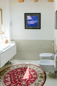 een badkamer met een wastafel, een toilet en een tapijt bij B&B RED WINE COUNTRY HOUSE in Castel San Pietro Terme