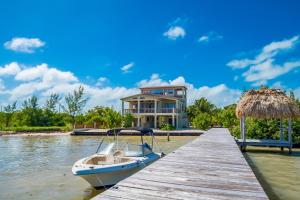 una barca attraccata a un molo di fronte a una casa di The Cottages at Island Pearl Gold Standard Certified a Caye Caulker
