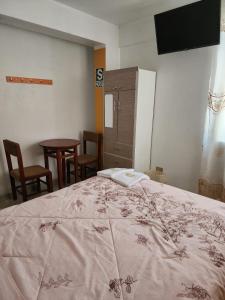 a bedroom with a bed and a table and chairs at Hostal Capac in Ayacucho