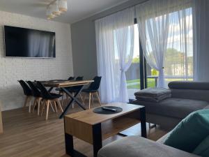 a living room with a couch and a table with a dining room at Sosnówka Lake Apartament in Sosnówka