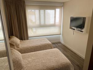 Habitación de hotel con 2 camas y TV en Alucinante departamento en La Perla 3 ambientes con aire acondicionado y calefacción central en Mar del Plata