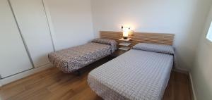 two beds in a room with a lamp on the wall at Balcón Playa Delicias in Águilas