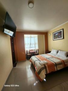 a bedroom with a bed and a flat screen tv at Hostal Capac in Ayacucho