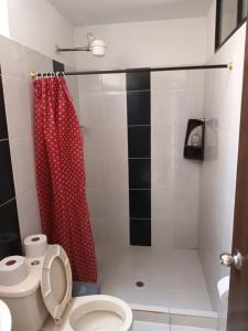 a bathroom with a red shower curtain and a toilet at Hotel Internacional Jardín in Jardin