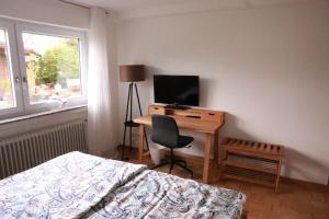 a bedroom with a bed and a desk with a television at Ferienappartement Albschätzle 