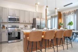 a kitchen with a large island with bar chairs at Brand New Top Elegance Vacation Home at Paradiso Grande in Orlando