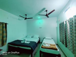 a bedroom with two beds and a ceiling fan at Surya cafe and stay sea view in Gokarna